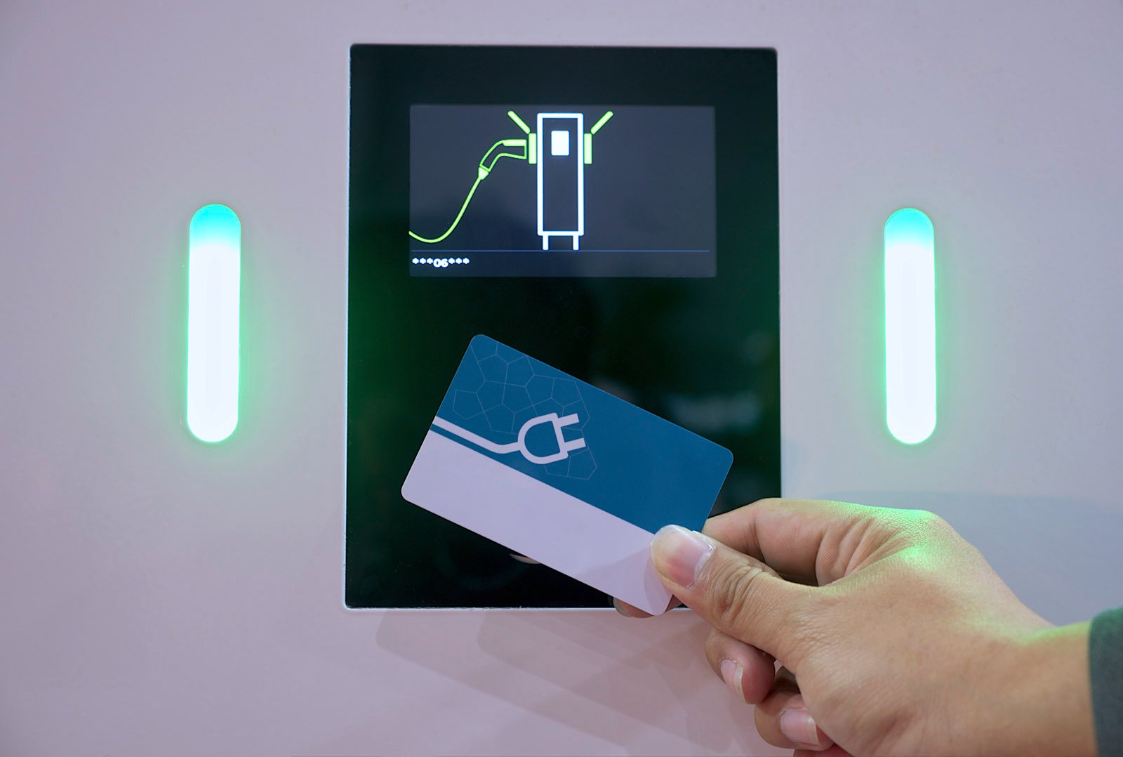 Hand hält Ladekarte vor ein Ladegerät mit Display und grün leuchtenden Indikatoren – Symbol für Zugang zu Ladeinfrastruktur per White-Label-Karte