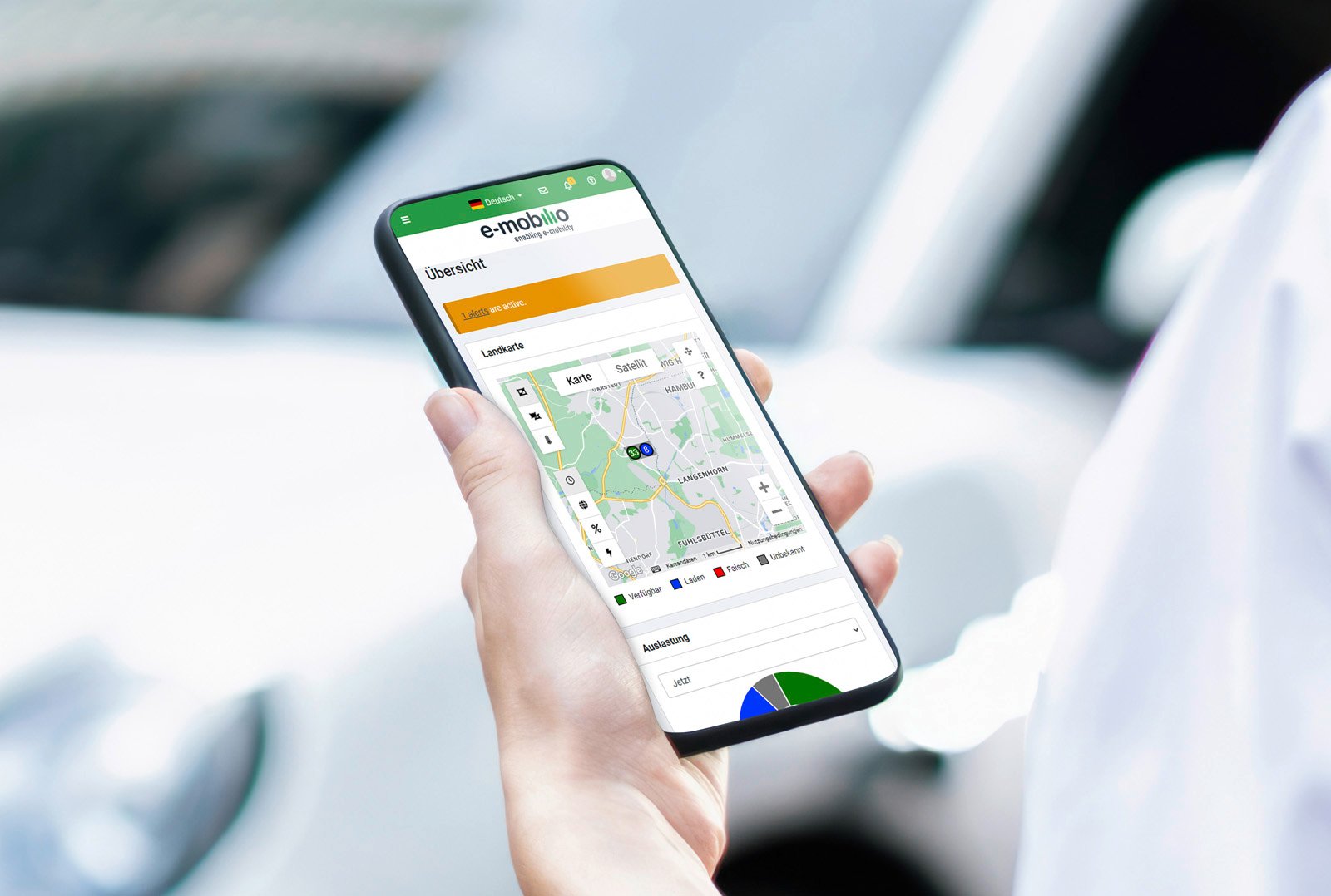 Hand hält Smartphone mit e-mobilio Abrechnungs-App zur Verwaltung von Ladevorgängen über Karte und Standortauswahl